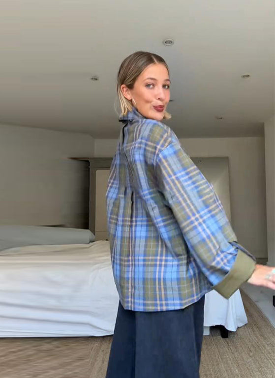 Person wearing a blue plaid shirt in a bedroom setting