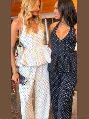 Two women wearing summer co-ord set with halter top and flowy trousers standing indoors.