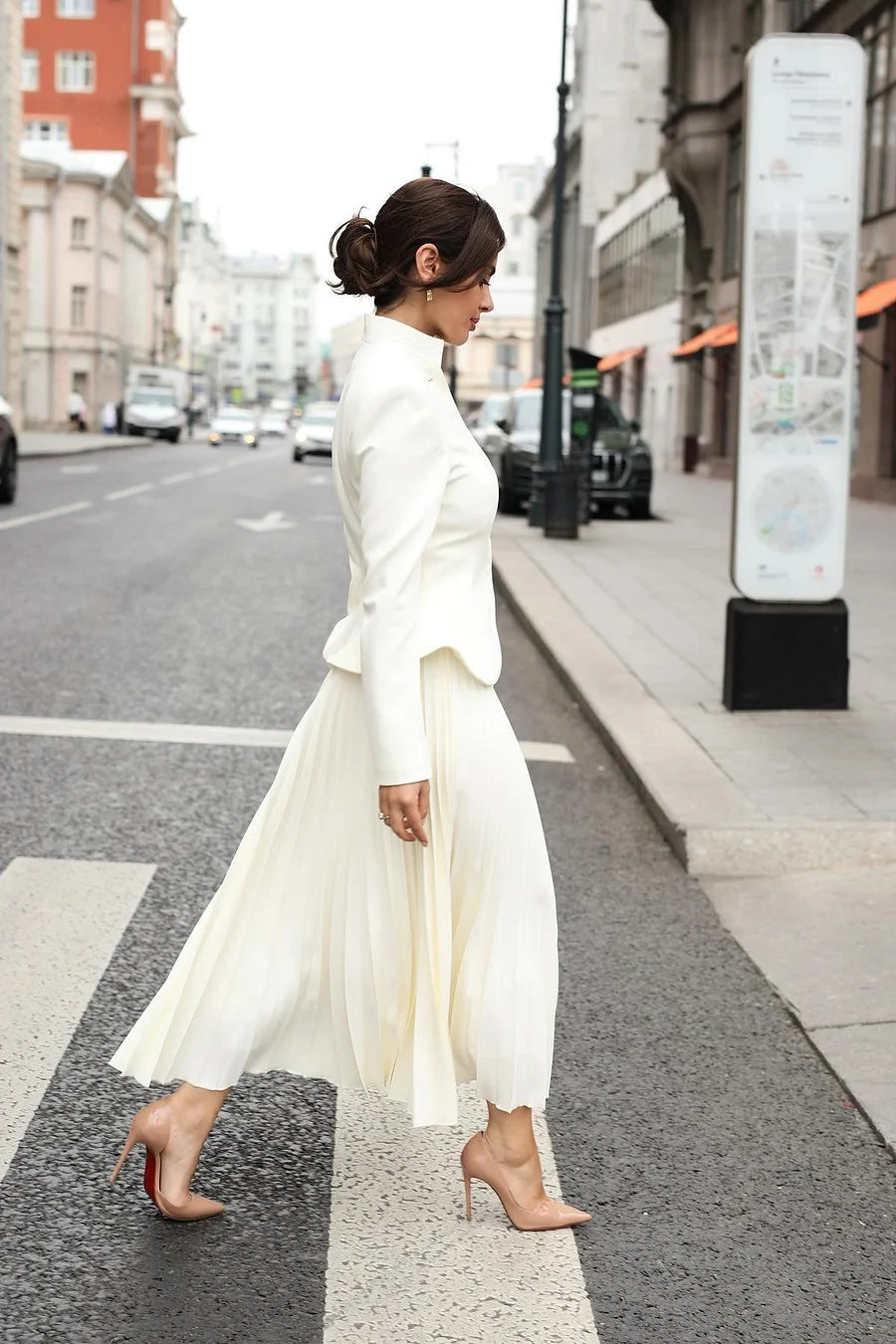 Woman in a white outfit walking on a city street