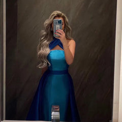 Woman taking a mirror selfie wearing a blue dress against a dark background