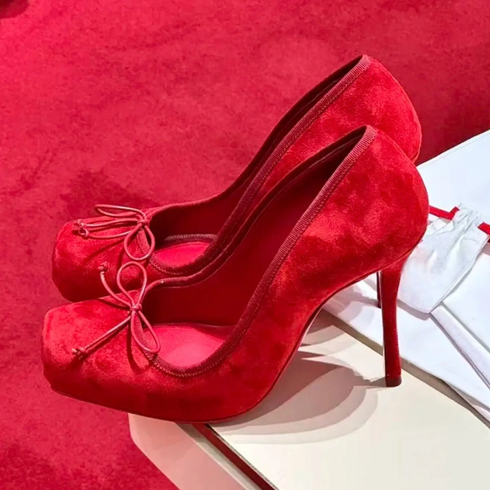 Red high-heeled shoes with a bow on a red background