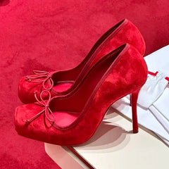 Red high-heeled shoes with a bow on a red background