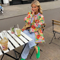 Model wearing a floral print quilted jacket at a cafe table