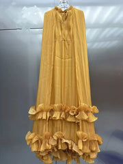 Yellow dress with ruffled layers on a hanger against a gray background