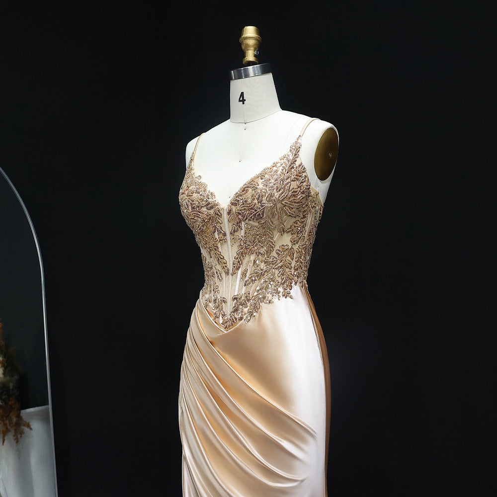 Mannequin wearing a beige evening gown with intricate lace detailing on a black background