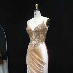 Mannequin wearing a beige evening gown with intricate lace detailing on a black background