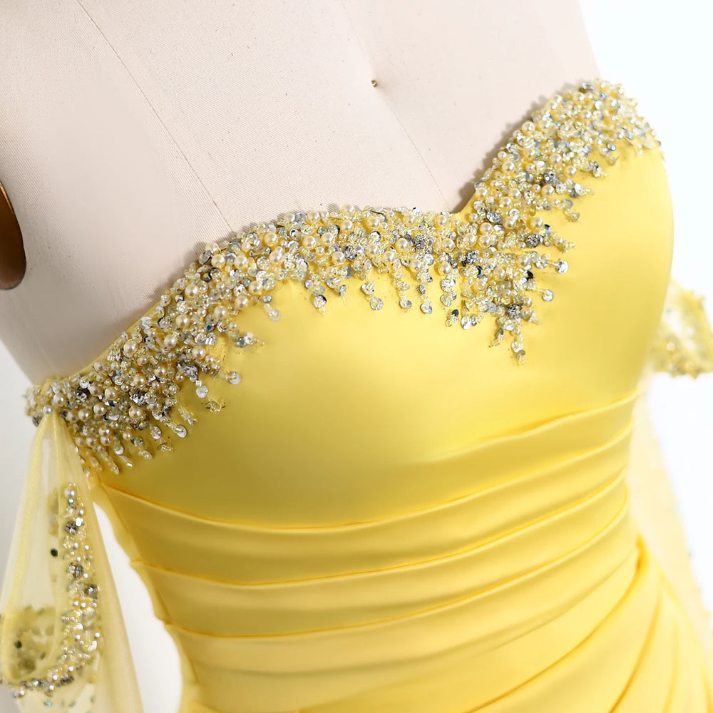 Yellow evening gown with beaded details on a white background