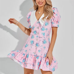 Pink mini dress with a white pointed collar, short puff sleeves, pearl button front, and a tiered ruffled hem.