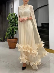 Woman wearing a long, flowing white dress with ruffled details in an indoor setting.