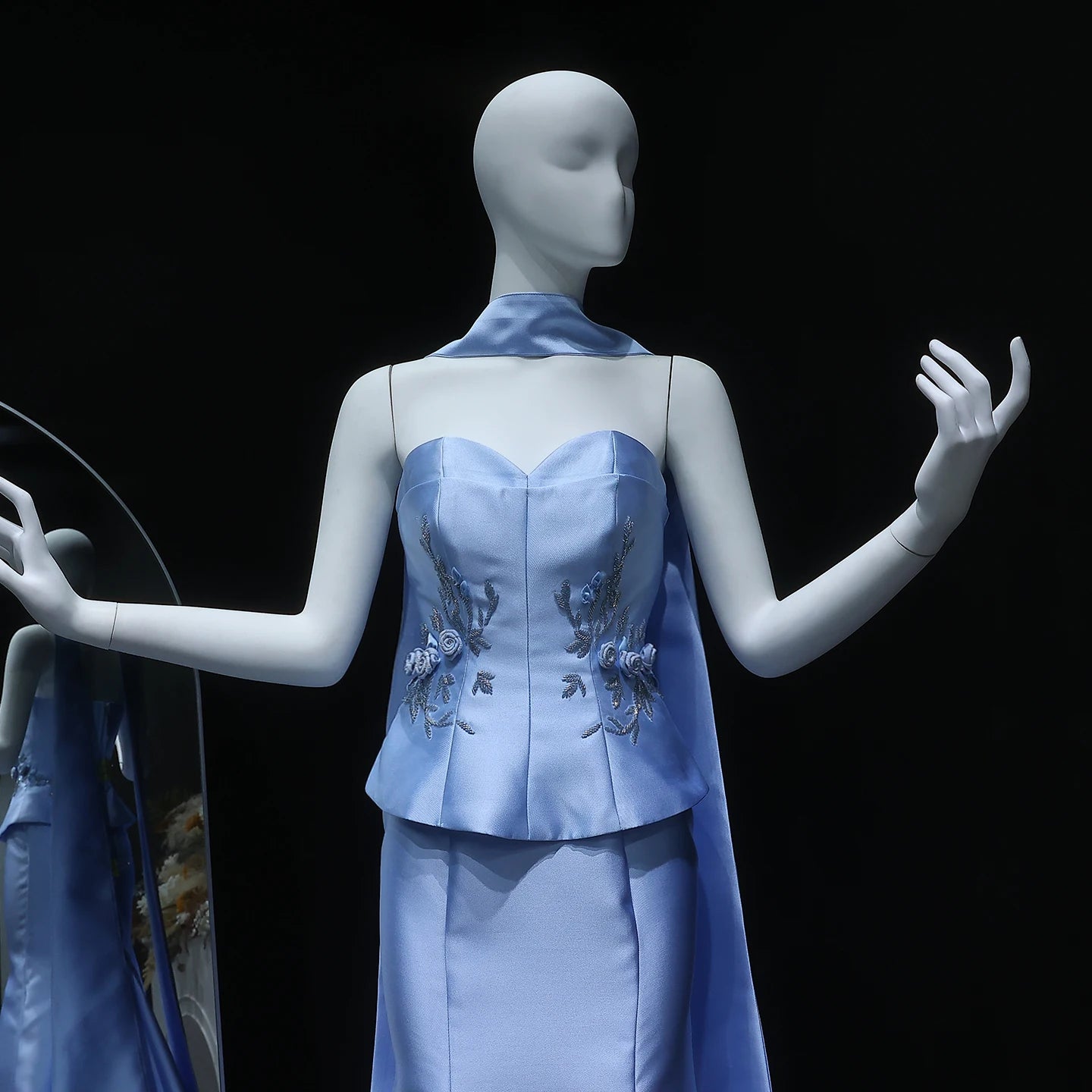 Mannequin wearing a light blue dress with floral embroidery on a black background