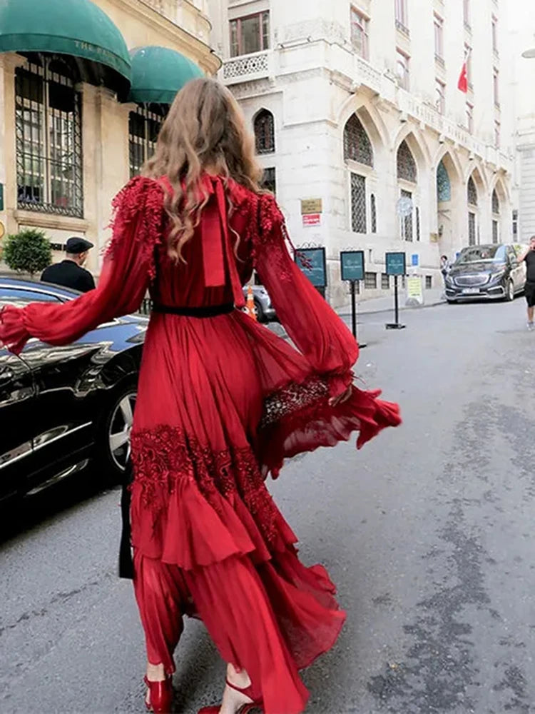 Back view woman in a formal red dress with belt shown at ankle length walking on a city street