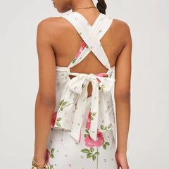 Back view of woman wearing a floral dress with a white criss-cross back design on a light grey background