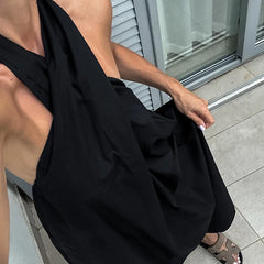 A woman holding a casual black vacation dress for woman with an open back in front of a building entrance.