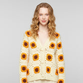 Woman wearing a sunflower-patterned cardigan against a plain background