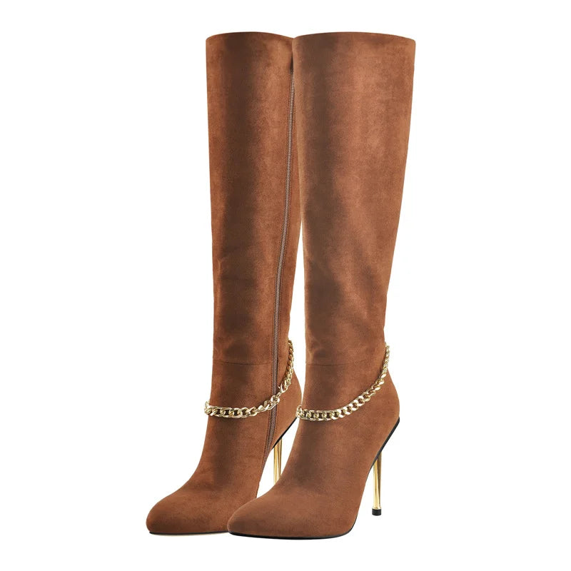 Pair of brown pointed toe knee-high boots with gold chain accents and stiletto heels