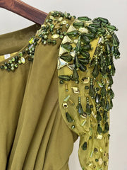 Green embroidered garment with intricate beadwork on a plain background