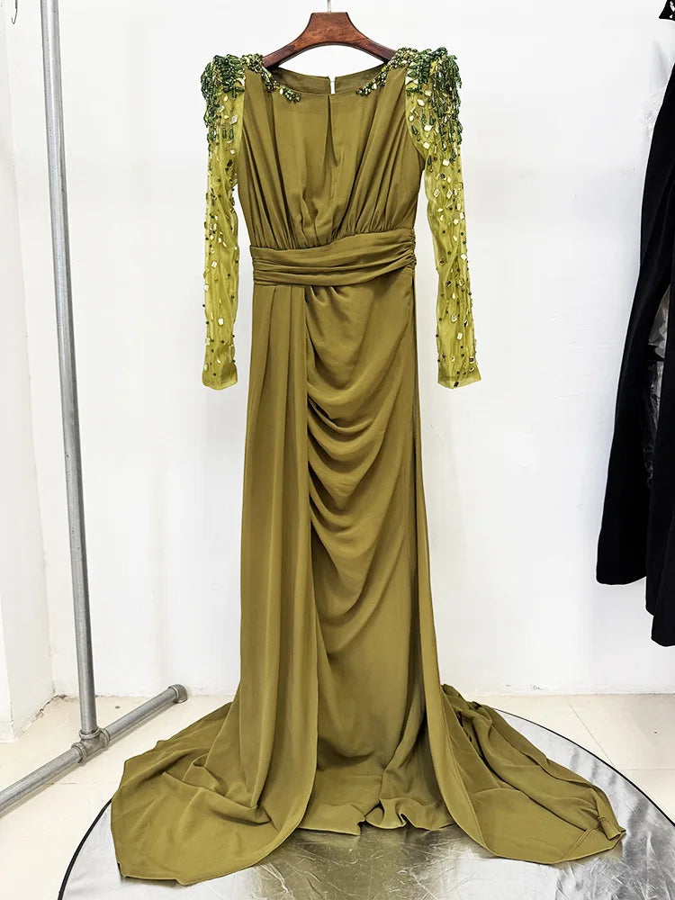 Green evening gown with long sleeves and embellishments on a white background