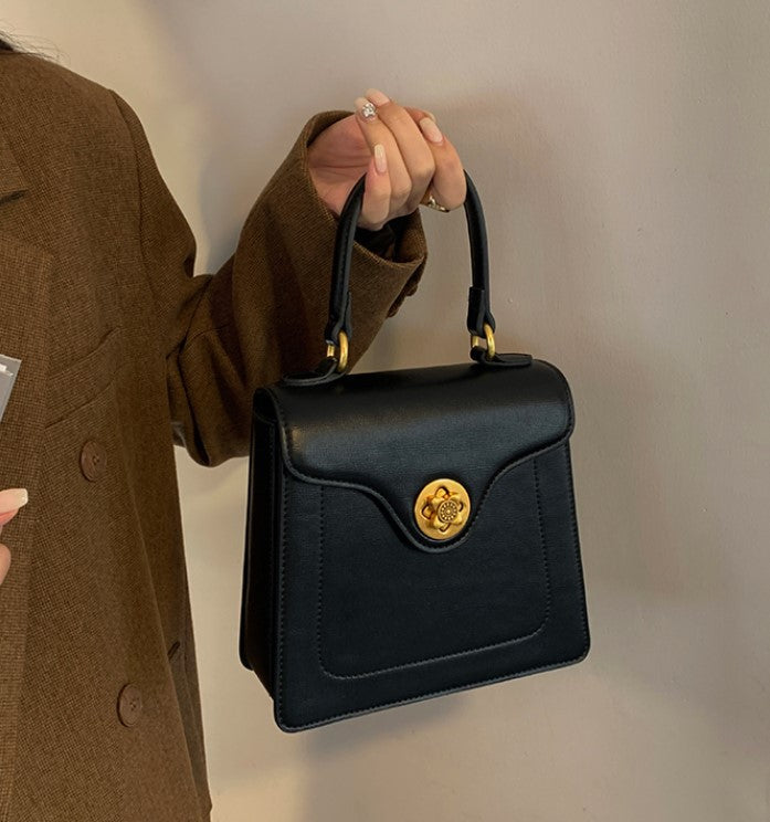 Black structured top handle bag with gold hardware