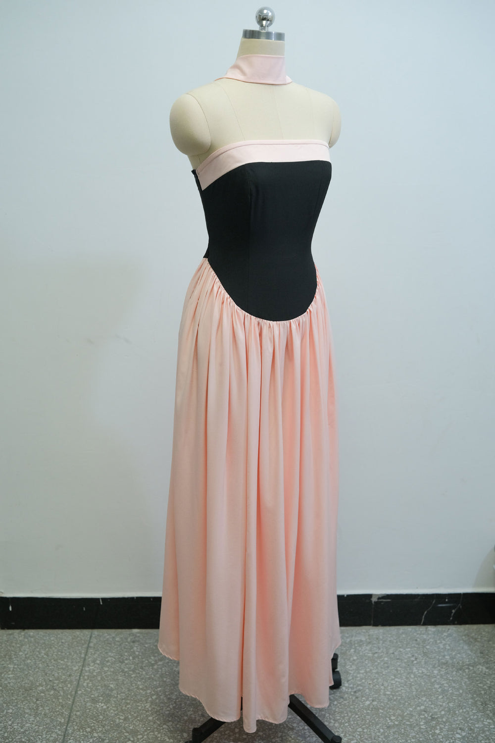 Mannequin wearing a black bodice with a pink skirt against a plain background