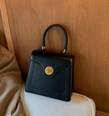 Close-up of a black structured top handle bag