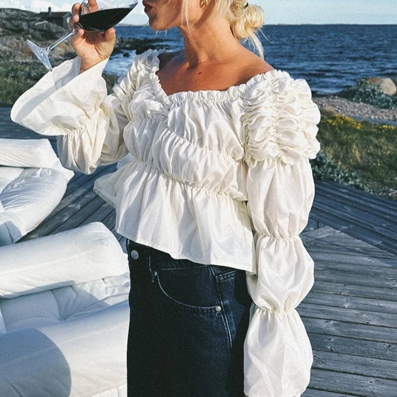 Woman in a white ruffled blouse by the sea