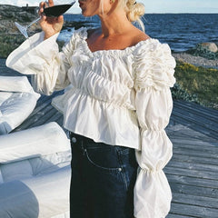Woman in a white ruffled blouse by the sea