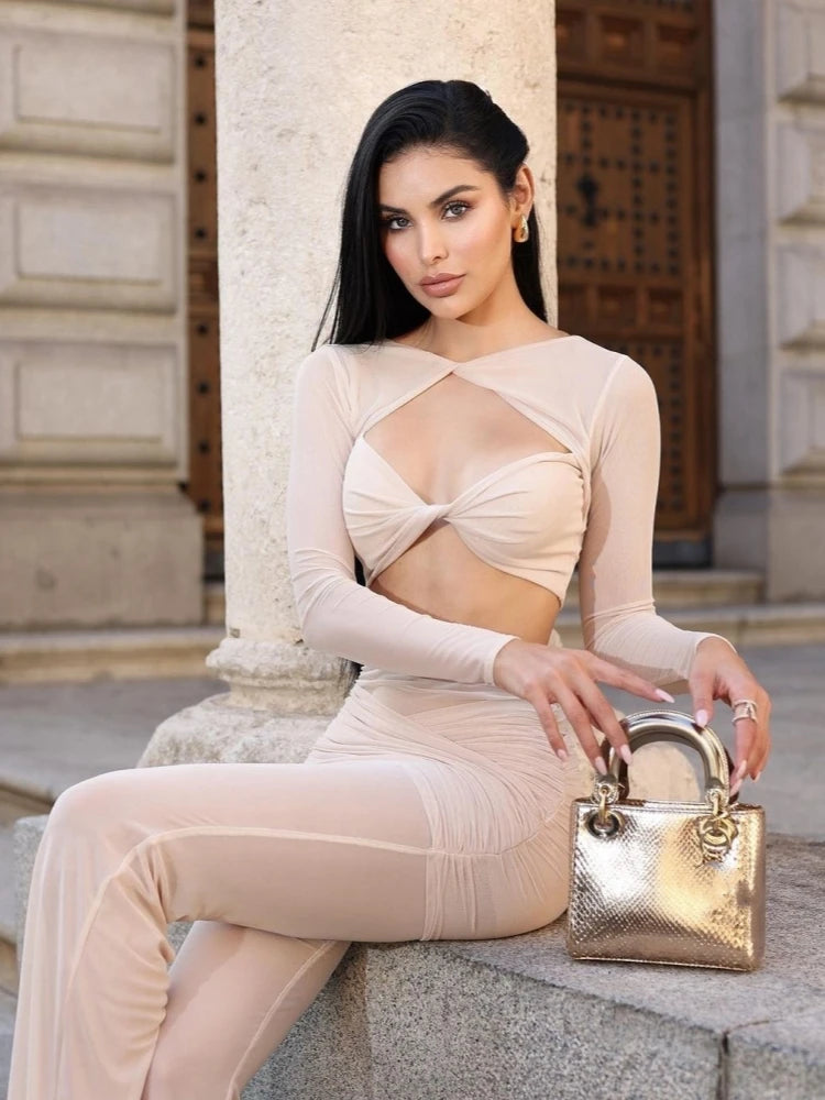 Woman in a beige outfit holding a gold handbag against an architectural background