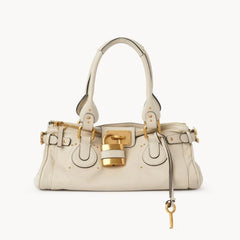 Cream leather tote bag with gold lock closure on a white background.