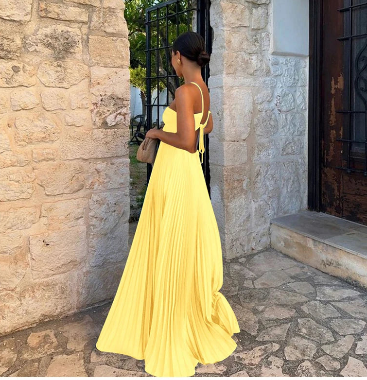 Woman in a yellow dress standing in front of a stone wall.