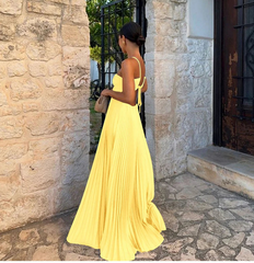Woman in a yellow dress standing in front of a stone wall.