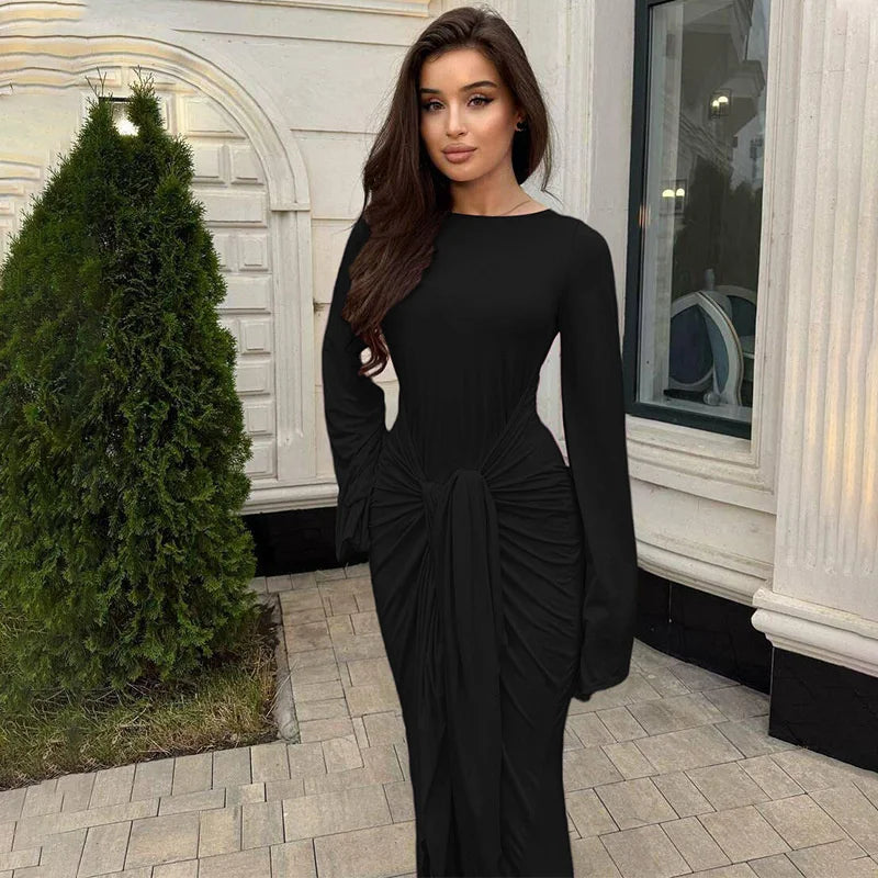 Woman in a black dress standing outdoors next to a building