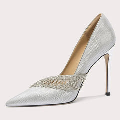Silver high-heeled shoe with embellishments on a light gray background