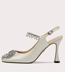 Silver high-heeled shoe with embellishments on a white background