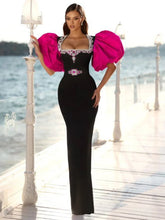 Woman in a black and pink dress standing on a dock by water