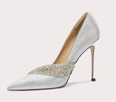 Silver high-heeled shoe with embellishments on a light gray background