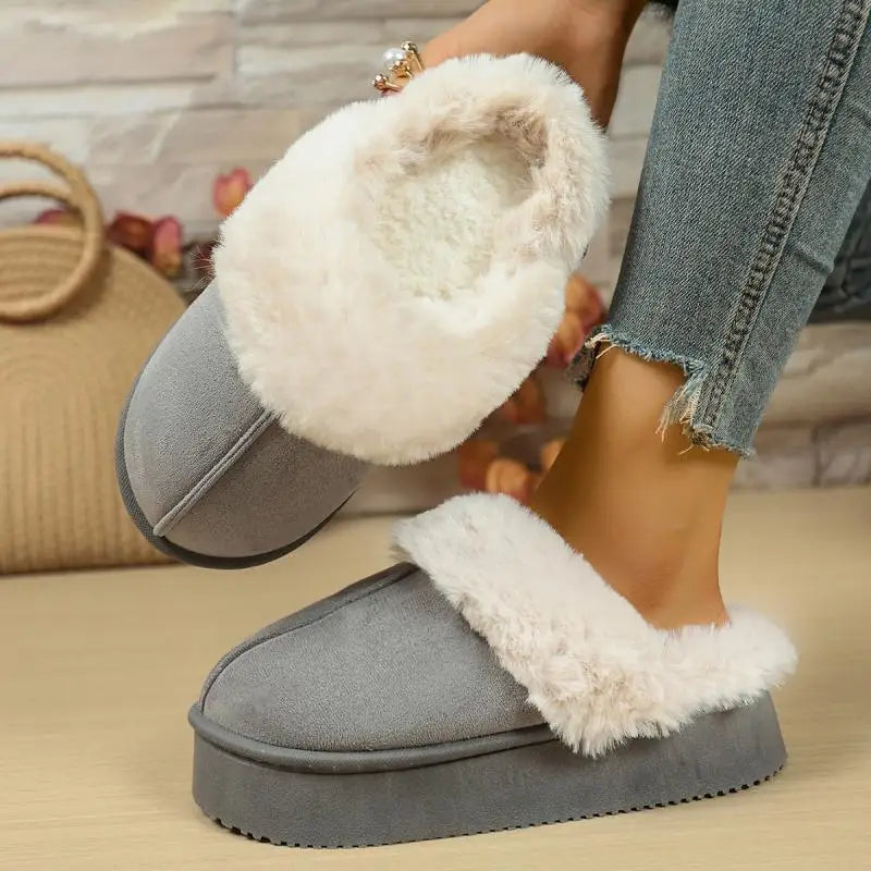 Gray slippers with white fuzzy lining worn by a person on a wooden floor.