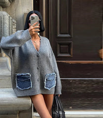 Person wearing a gray cardigan with denim pocket details, taking a selfie outdoors.