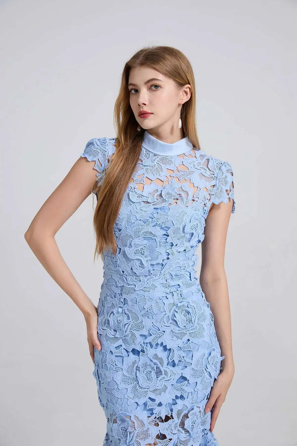 Woman wearing a light blue lace dress against a plain background