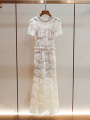 White lace dress with embellishments on a wooden hanger against a neutral background