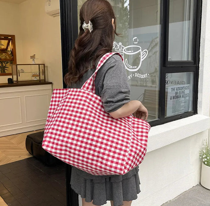 Person holding a red and white checkered bag in front of a store entrance.
