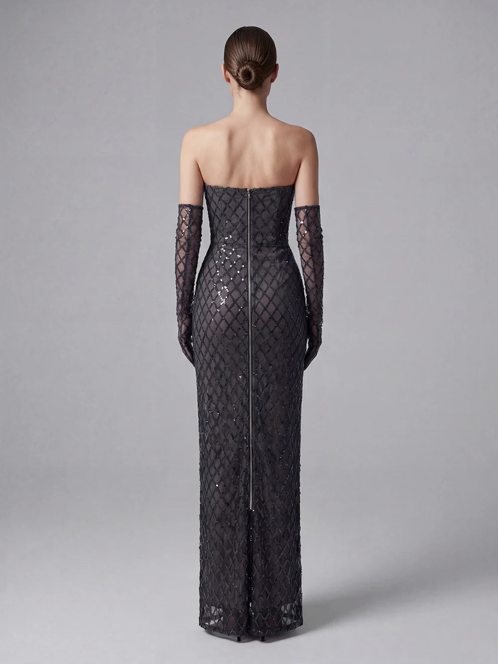 Black strapless evening gown with lace detailing on a gray background