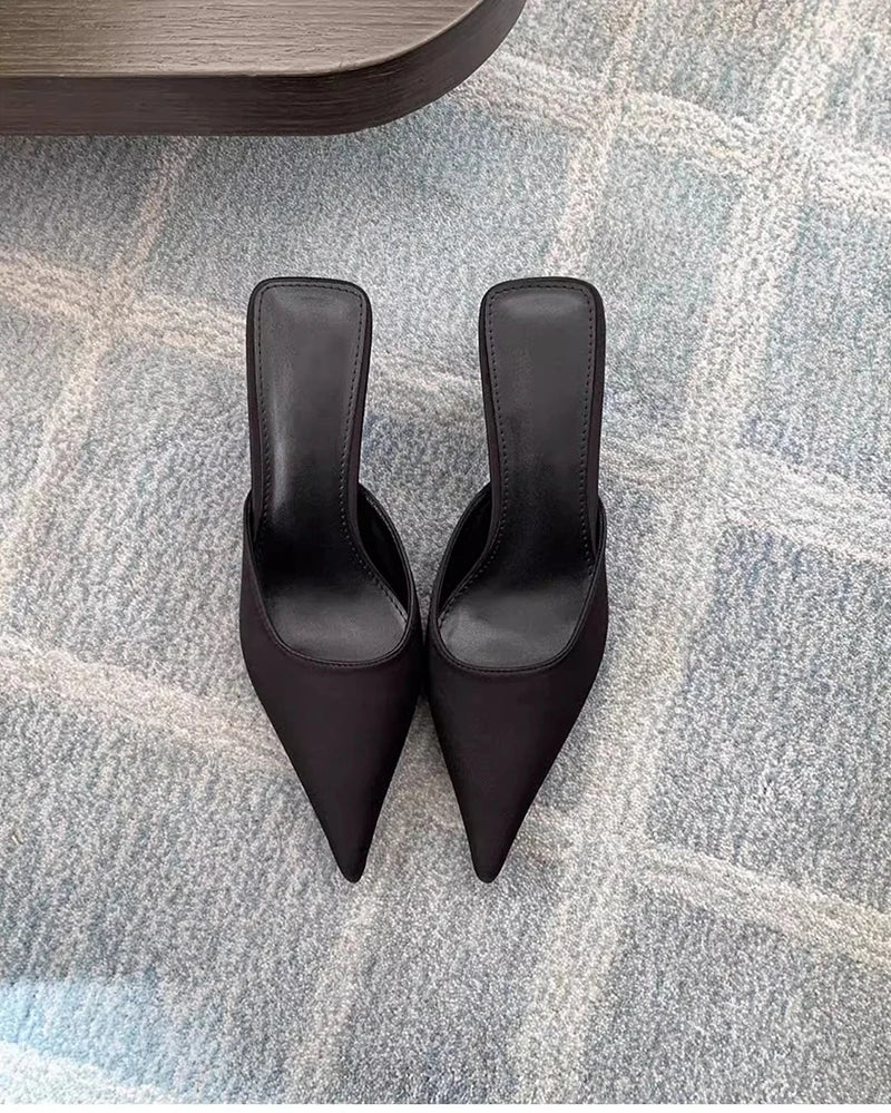 Pair of black high-heeled shoes on a textured gray floor.