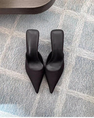 Pair of black high-heeled shoes on a textured gray floor.