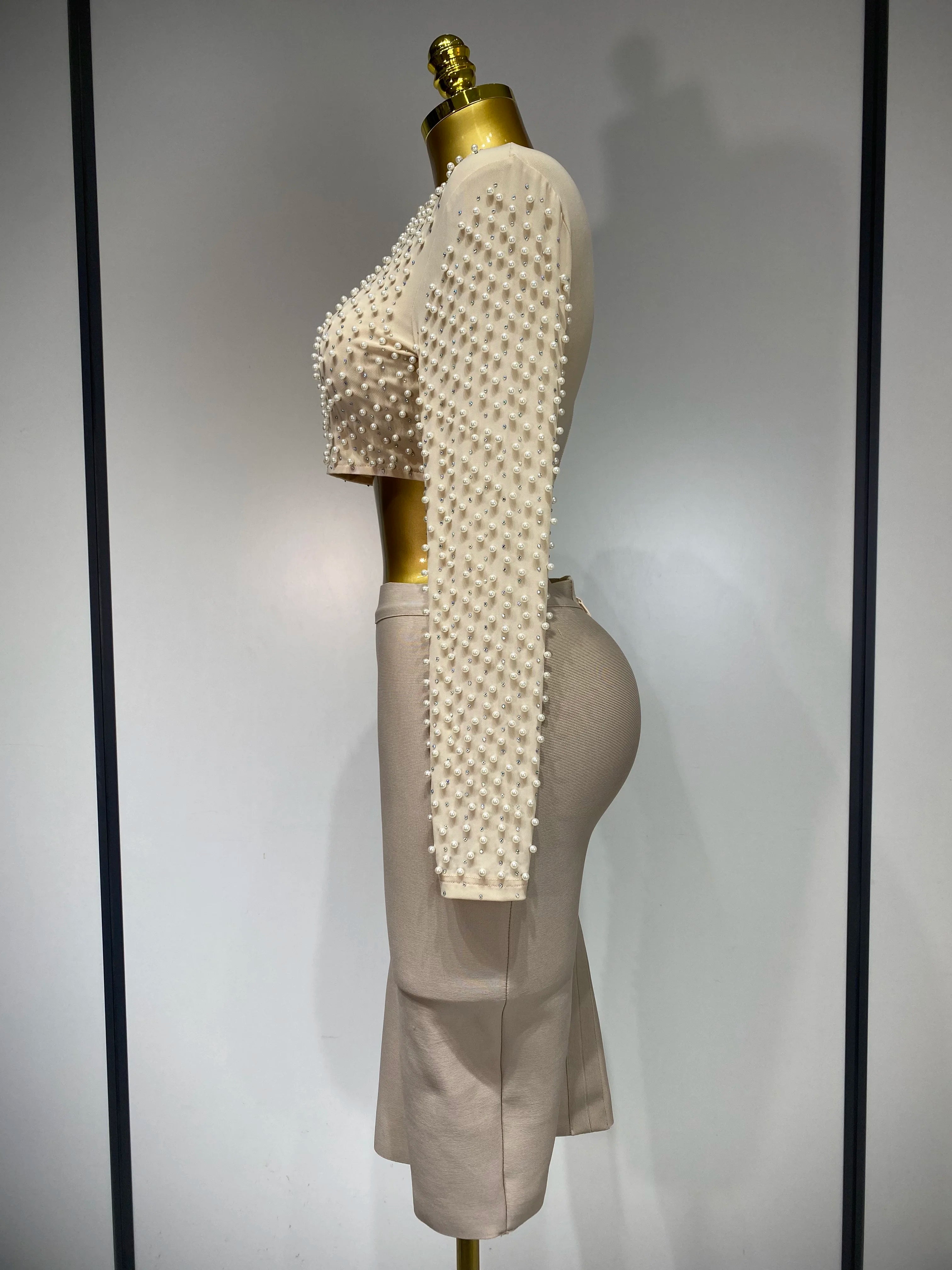 Mannequin wearing a beige outfit with textured top and pants against a plain background