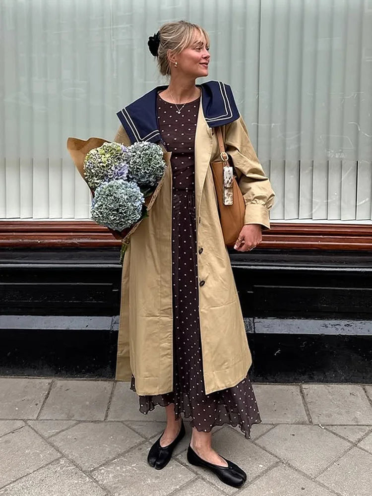 Woman wearing a trench coat with navy sailor collar and polka dot dress