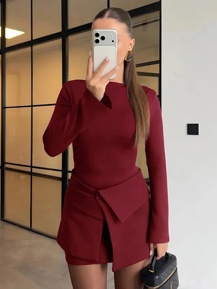Person wearing a burgundy outfit with a matching skirt, standing indoors.