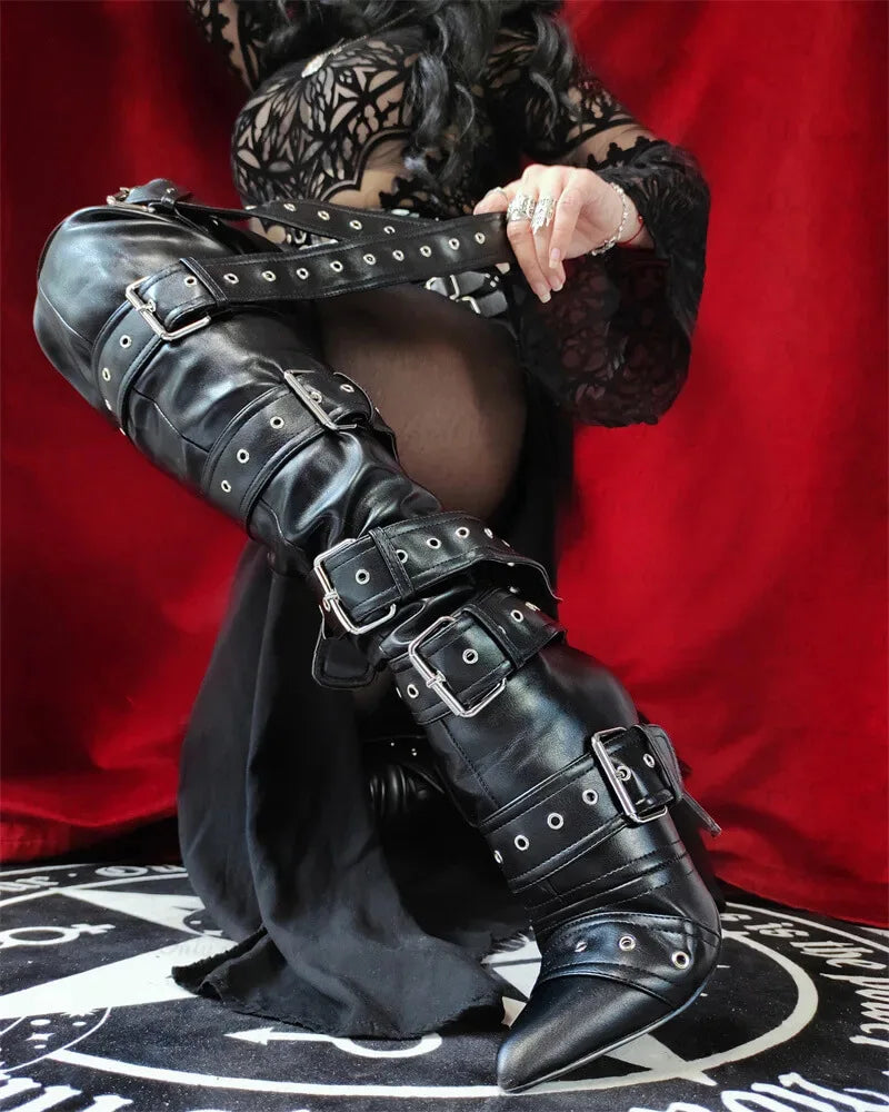 Black leather knee-high boots with buckles on a red background