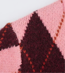 Close-up of a pink and maroon knitted fabric with a geometric pattern on a white background.