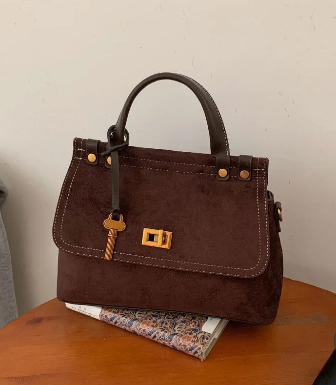 Brown handbag with gold accents on a wooden surface