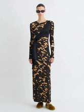 Model wearing a long black dress with a gold animal print pattern
